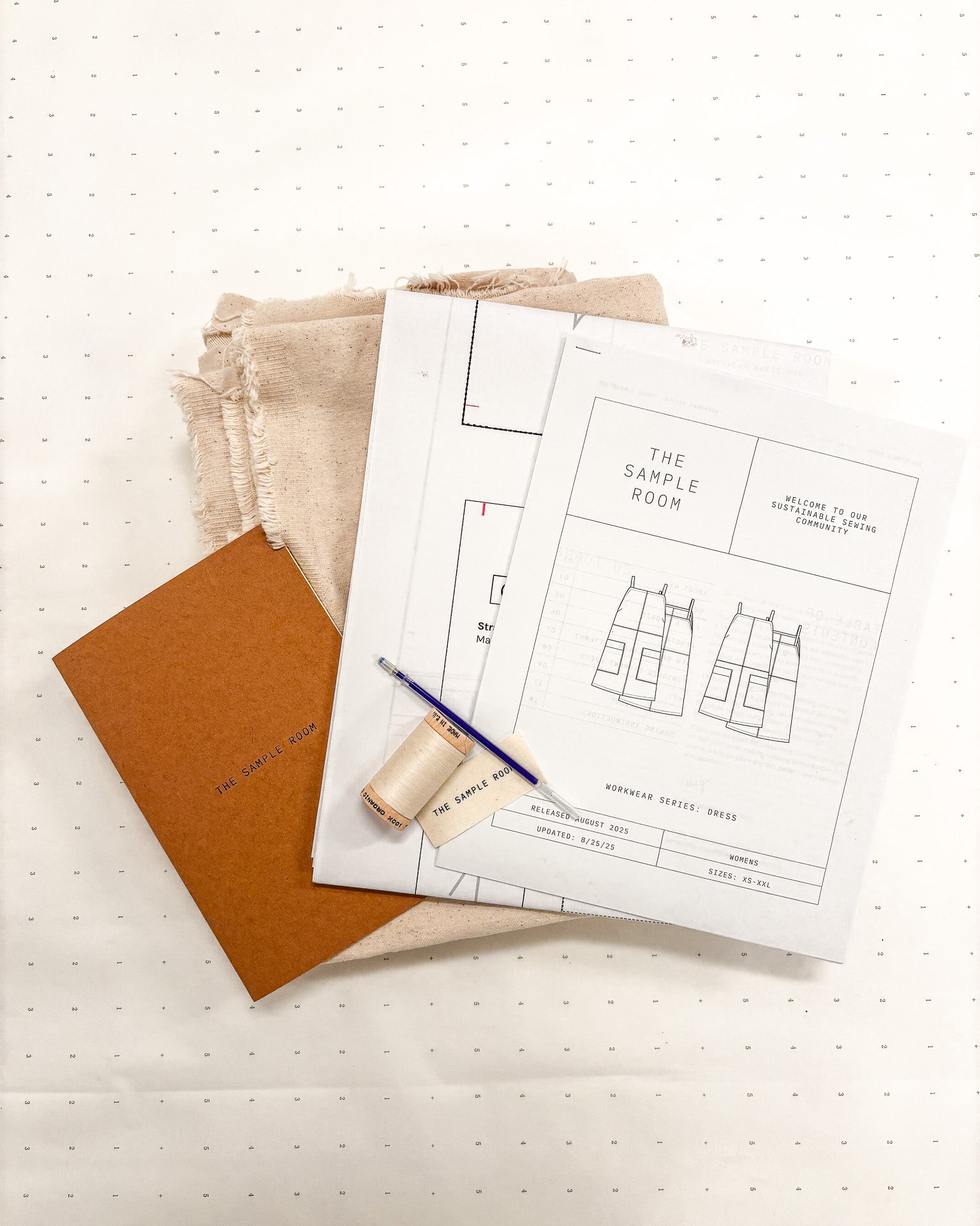 Sewing pattern book with fabric and a pencil on a white surface
